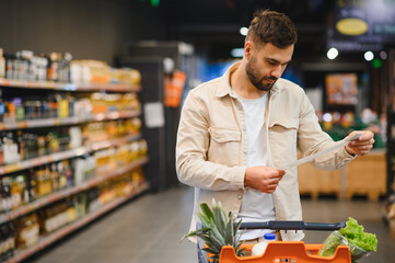Man checking shopping list in supermarket aisle