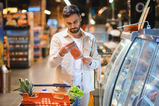 Man shopping for fish examining food label in supermarket