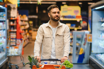 Young man grocery shopping in supermarket aisle