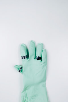 Overhead view of a green rubber glove wearing three silver rings
