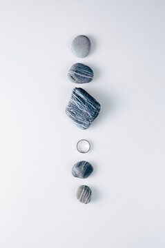 Overhead view of five assorted Stones and a silver ring arranged in a row on a white background
