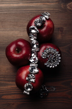 Overhead view of a costume jewellery on four red apples on a wooden table