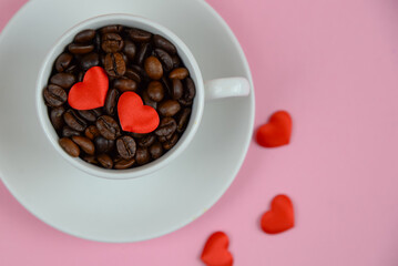 Cup with coffee beans and red hearts on a pink background, Valentine's Day theme