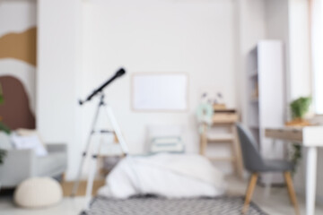 Blurred view of stylish children's room with bed and modern telescope