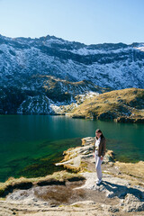 Young smiling woman standing on rocky shore of Balea Lake in Fagaras Mountains. Transfagarasan Highway, Romania