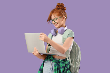 Cute schoolgirl with modern laptop and backpack on lilac background