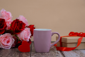 Pink cup of coffee on table with gift and roses