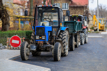 Obraz premium Blue tractor on urban street with trailers during road construction