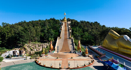 Grand temple staircase and reclining Buddha at forested hillside