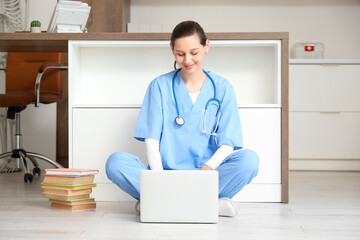 Female medical intern studying with laptop in clinic