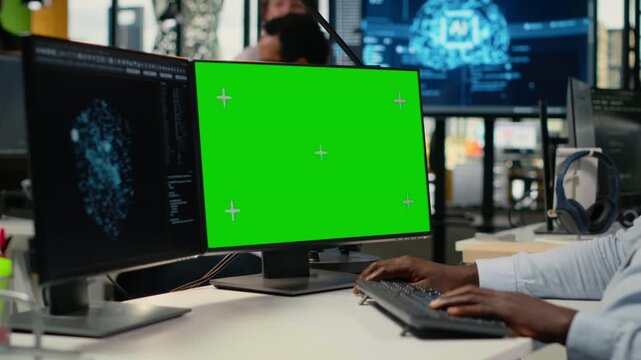 Green screen PC used by technician in office using AI to optimize company systems performance. Worker in startup office uses artificial intelligence tech on mockup computer to automate tasks, camera B