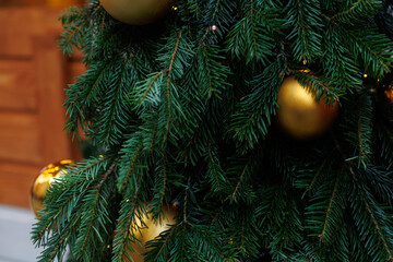 Golden Christmas bauble on fir tree with festive lights and soft bokeh