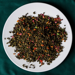 Loose herbal tea on white plate with green mat