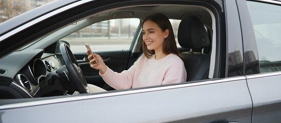 Young woman driving car and using smartphone while smiling