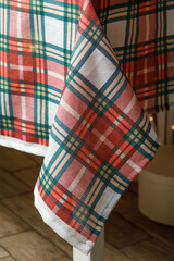 Hanging corner of plaid tablecloth over wooden floor

