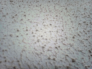 Macro close-up of thick, rough white stucco, popcorn or gotele texture wall finish. Exterior mural surface with uneven gotel&eacute; and woodchip effect. Grainy paint, vintage style, outdoor home decor. 