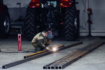 Industrial worker in protective mask welding steel parts
