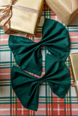 Gift boxes and folded green napkin on plaid Christmas table