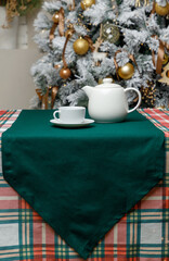 Teapot and cup on green runner with Christmas tree
