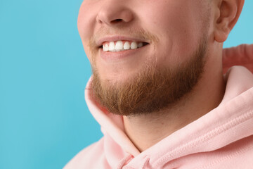 Obraz premium Smiling young bearded man on blue background, closeup