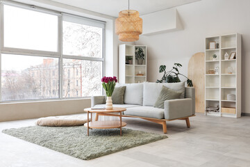 Beautiful interior of comfy room with grey sofa, carpet and large window