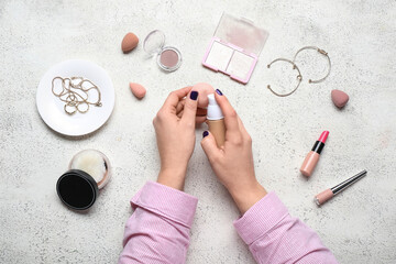 Fototapeta premium Female hands with different decorative cosmetics, accessories and makeup sponges on white background
