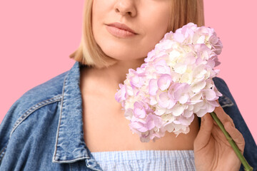 Young woman with bob hairstyle holding hydrangea flowers on pink background