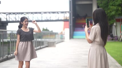 Woman posing and dancing while friend records video with smartphone outdoor, social media content creation, social media trend and influencer marketing lifestyle, talent management and live streaming - Powered by Adobe