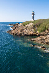 Modern black and white lighthouse standing on a rocky cliff by the deep blue sea under a clear sky, Isla de Pancha, Ribadeo, Galicia, Spain