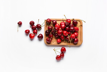 Wooden board with sweet cherries on white background
