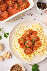 Plate of boiled pasta with tomato sauce and meat balls on white table