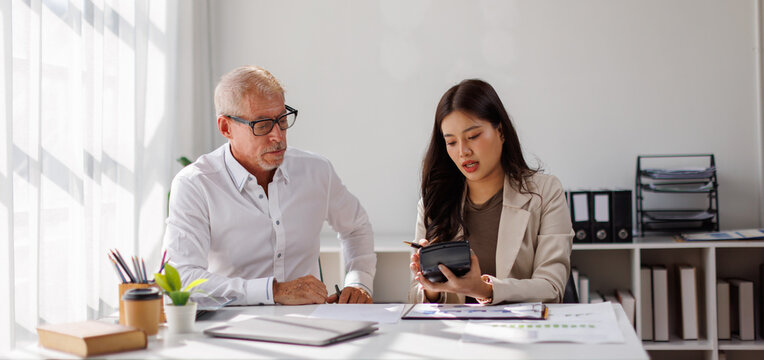 Team of business using calculator and laptop for do math finance on wooden desk in office and business working background, tax, accounting, statistics and analytical research concept

