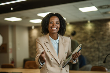 Professional businesswoman extending hand for friendly handshake in office