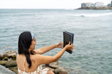 Young woman enjoying a video call by the ocean