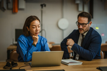 Business colleagues collaborating on laptop during office meeting