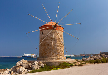 Stone windmills along Mandraki harbor promenade in Rhodes, Greece