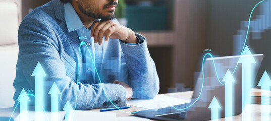 In a contemporary office, an Indian businessman thoughtfully examines work on his laptop. He considers strategies and solutions to enhance productivity during his workday.