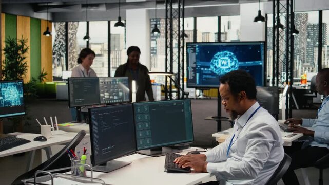 Technician in office solving tasks with artificial intelligence LLM chatbot answering prompts. African american man at work using PC to interact with large language model program, camera A