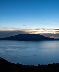 Island silhouette at dusk above calm blue sea
