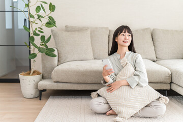 Asian woman using smartphone app while sitting in the living room
