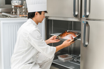 A male chef in a cook coat taking ingredients out of the refrigerator