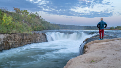 Naklejka premium lonely man contemplating the Norden Chute on Niobrara River in Nebraska, late summer sunrise scenery