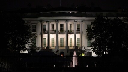 Lights shine on the Whitehouse and its surroundings at night in Washington DC while people visit...