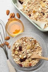 Making granola. Flat lay composition with oat flakes, dried fruits, almond nuts and honey on grey textured table