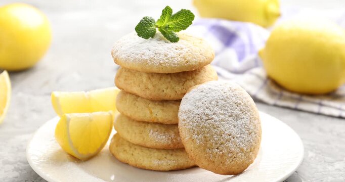 Woman putting mint onto tasty lemon cookies at grey table, closeup