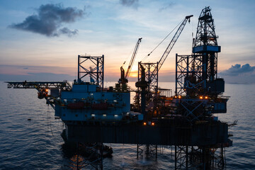 Fototapeta premium Aerial view of offshore jack up rig in a shipyard during sunset for oil and gas exploration and production.