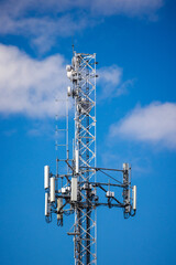 Modern cellular tower with multiple antennas and radio equipment against bright blue sky