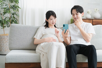 スマートフォンを操作する妊婦と夫　ライフスタイルイメージ