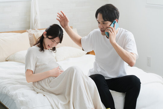 妊婦が破水してスマートフォンで電話をする夫　ライフスタイルイメージ