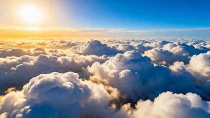 Aerial view of fluffy clouds illuminated by the rising sun above a sea of cumulus clouds under a clear blue sky